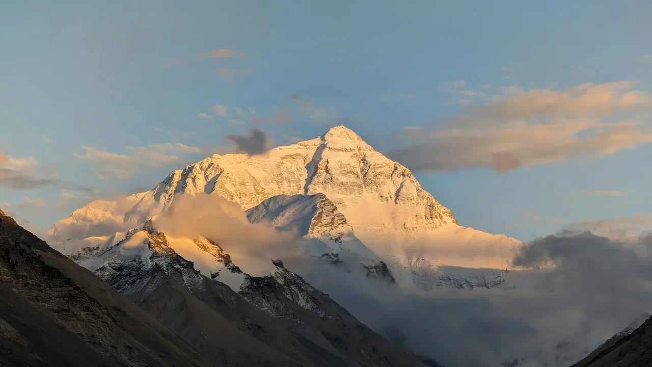 Mount Everest at sunset, its snow lit gold above the clouds.
